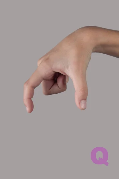 Símbolo Q en lenguaje de gestos. Carta hecha por mano humana sobre gris — Foto de Stock