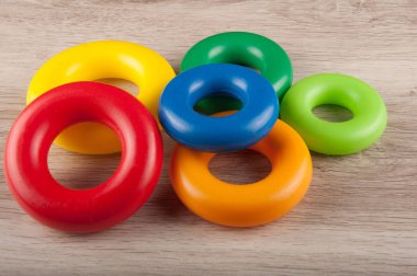 Ahşap arka plan üzerinde çok renkli plastik halkalar yığını