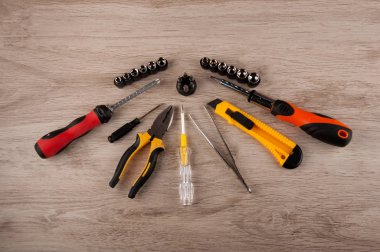 Farklı aletler: tornavida, cımbız, bıçak, pense ve vidalar ahşap masanın üzerinde duruyordu