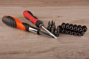 İki kırmızı ve turuncu tornavida ve farklı vidalar ahşap masada yatıyordu.