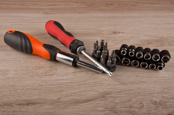 İki kırmızı ve turuncu tornavida ve farklı vidalar ahşap masada yatıyordu.