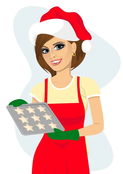 Fiatal gyönyörű nő santa kalap tartja a cookie-k sütés tálca — Stock Vector