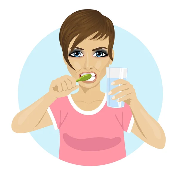 Mujer joven cepillándose los dientes y sosteniendo un vaso de agua — Vector de stock