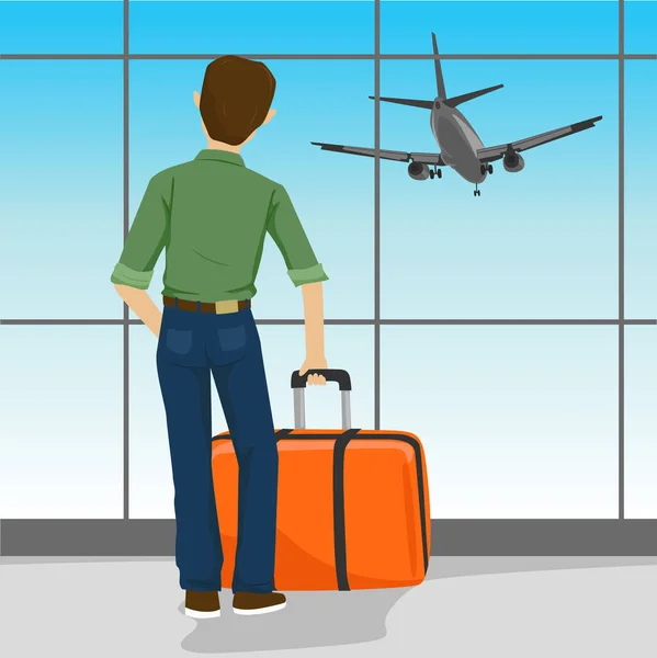 Rear view of man standing with suitcase in airport watching landing aircraft — Stock Vector