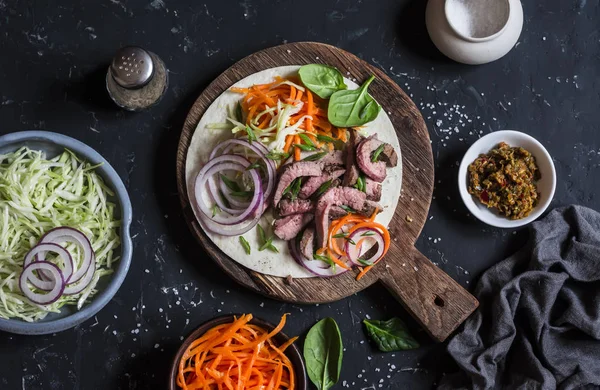 Steak tortilla with pickled carrots and cabbage on a wooden cutting board on dark background, top view — Stock Image Steak tortilla with pickled carrots and cabbage on a wooden cutting board on dark background, top view Royalty Free Stock Photos