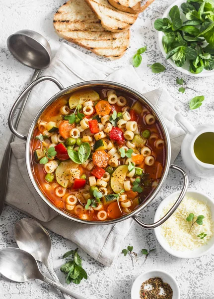 Minestrone soup in a pan on a light table, top view. Delicious vegetarian food concept. Flat lay — Stock Image Minestrone soup in a pan on a light table, top view. Delicious vegetarian food concept. Flat lay Royalty Free Stock Images