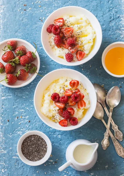 Sweet rice porridge with berries on a light background, top view. Healthy breakfast or dessert