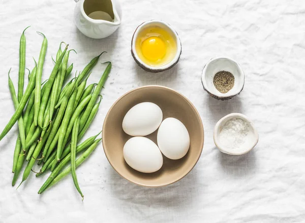 Raw ingredients for cooking breakfast - eggs, green beans, olive oil, spices on a white background, top view. Flat lay