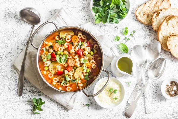Minestrone soup in a pan on a light table, top view. Italian soup with pasta and seasonal vegetables. Delicious vegetarian food concept. Flat lay — Stock Image Minestrone Soup Pan Light Table Top View Italian Soup Pasta Stock Image