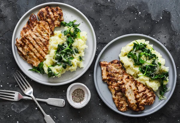 Roast pork with mashed potatoes and spinach - comfort winter meal on a dark background, top view
