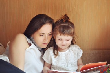 Anne ve kızı kitap okuyorlar.