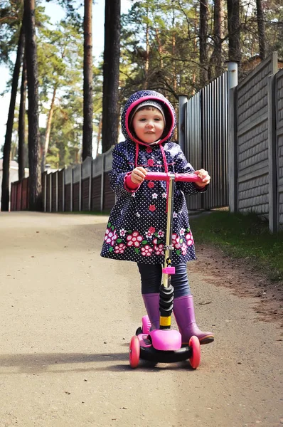 Kleines Mädchen in rosa auf einem Motorroller — Stockfoto
