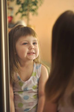 sevimli küçük kız ayna gülüyor görünüyor. küçük güzellik