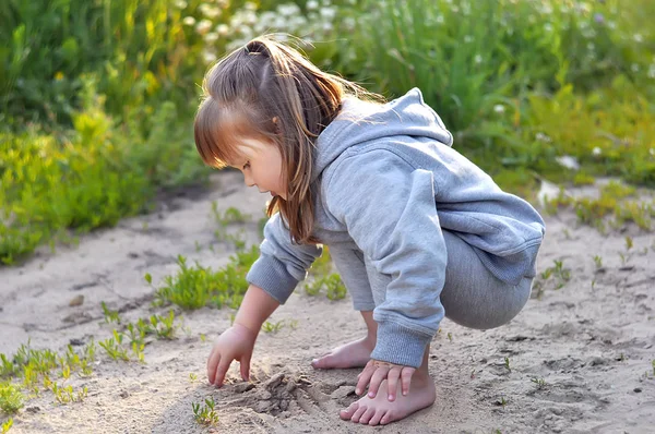 Милая маленькая девочка играет с песком в лесу — стоковое фото