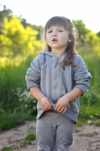 Niña jugando en el soleado bosque floreciente. Un niño pequeño. Los niños juegan al aire libre. Diversión de verano para familia con niños . — Foto de Stock