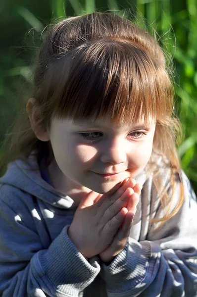 Niña jugando en el soleado bosque floreciente, mirando desde la hierba. Niño recogiendo flores de altramuz. Los niños juegan al aire libre. Diversión de verano para familia con niños . — Foto de Stock