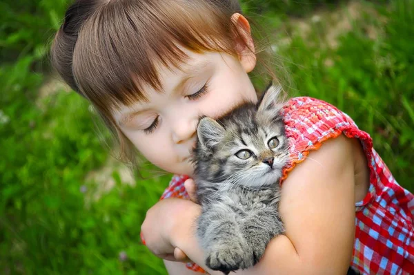Retrato ao ar livre de uma menina fofa com gatinho pequeno, menina brincando com gato no fundo natural — Fotografia de Stock