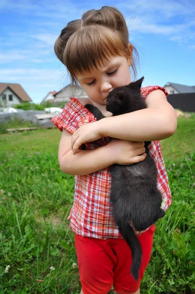 Außenporträt eines niedlichen kleinen Mädchens mit kleinen Kätzchen, Mädchen spielt mit Katze auf natürlichem Hintergrund — Stockfoto
