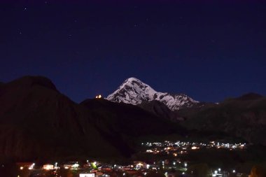 Kazbek Dağı ile Gergeti Trinity Kilisesi, Georgia silüeti üzerinde gece gökyüzü