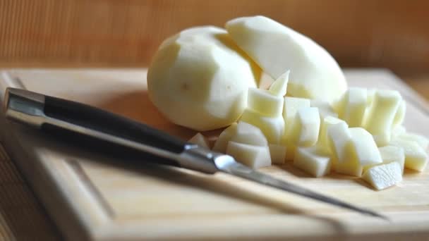 Potatos gesneden voor het koken van maaltijden. Aardappelen op een snijplank gesneden in stukken. Keukenmes. — Stockvideo