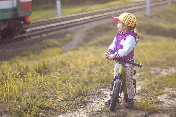 Kleines Mädchen mit Fahrrad beobachtet einen Zug — Stockfoto