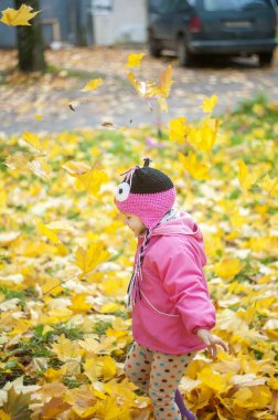 sonbahar Park, düşen yapraklar arasında eğleniyor güzel mutlu bebek kız