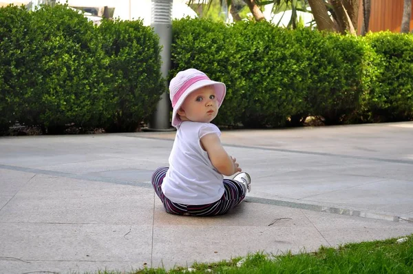 Linda niña sentada en el suelo en el parque — Foto de Stock