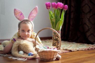 Tavşan kulakları Paskalya gününde giyen sevimli küçük çocuk. Sepet boyalı yumurta ile yatan kız.
