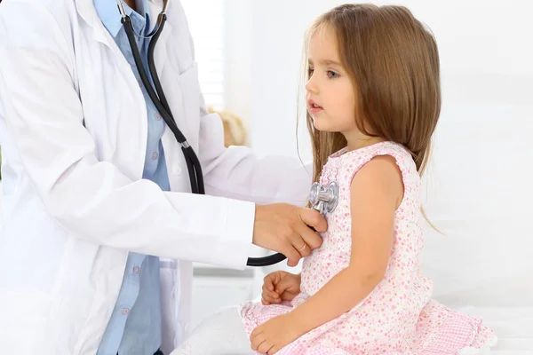 Doktorn undersöker en liten flicka med stetoskop — Stockfoto