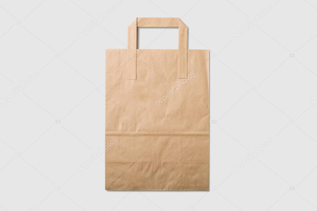 Mockup of a blank kraft paper shopping bag with handles on light grey background. High resolution.