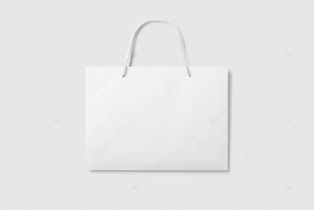 Mockup of a blank white paper shopping bag with handles on light grey background. High resolution.