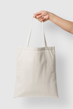 Açık gri arkaplanda boş bir Tote Tvas Çantasının kadın eli modeli. Yüksek çözünürlük. 