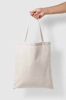 Açık gri arkaplanda boş bir Tote Tvas Çantasının kadın eli modeli. Yüksek çözünürlük. 