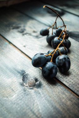 Eski ahşap bir arka planda siyah üzümün küçük bir dalı.