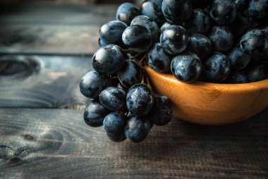 Bambu kasesinde bir demet siyah üzüm. Makro