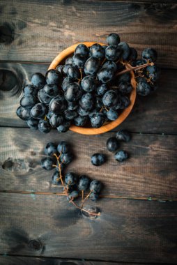 Bambu kasesinde bir demet siyah üzüm. Üst Manzara. Kalitesiz ahşap arka plan