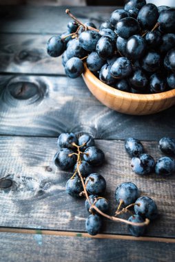 Bambu kasesinde bir demet siyah üzüm. Dikey