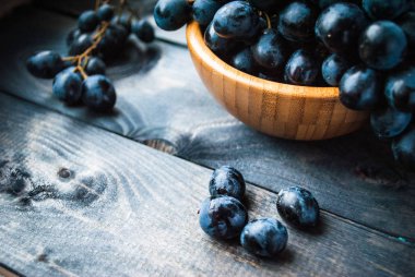 Küçük bir bambu kasesinde bir demet siyah üzüm