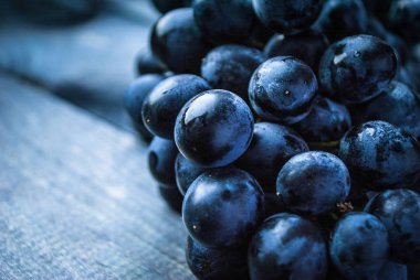 Ahşap bir arka planda bir demet siyah üzüm. Kapat.