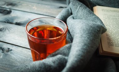 Tahta bir arka planda çay, kitap ve battaniye