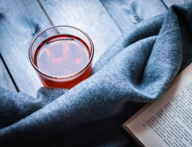 Tahta bir arka planda çay, kitap ve battaniye