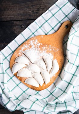 Mutfak tahtasına un serpiştirilmiş çiğ hamur tatlısı ve çizgili havlu.