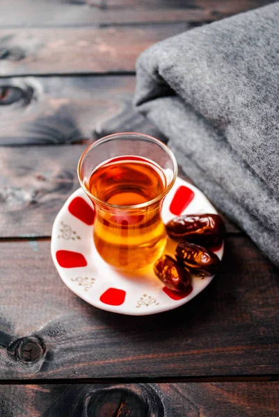 A glass of black tea and dates on a saucer — Stock Photo, Image