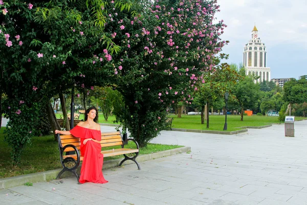 Ung kvinna sitter på en bänk i parken — Stockfoto