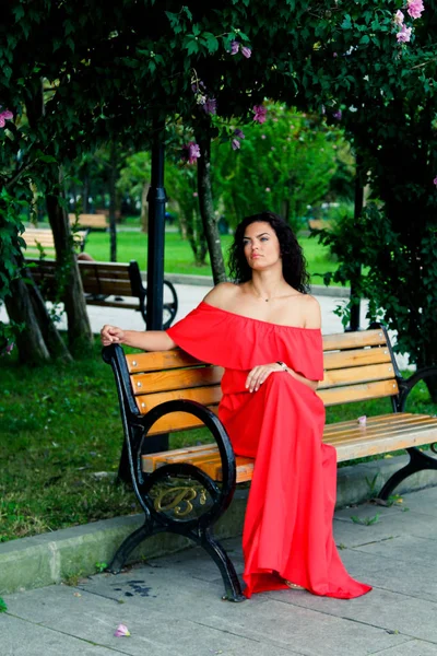 Молодая женщина сидит на скамейке в парке — стоковое фото