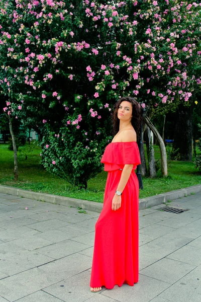 Porträtt av en vacker brunett kvinna nära rosa blommor — Stockfoto