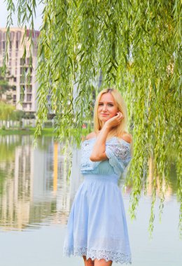 Göl kenarında ayakta mavi bir elbise güzel kız.