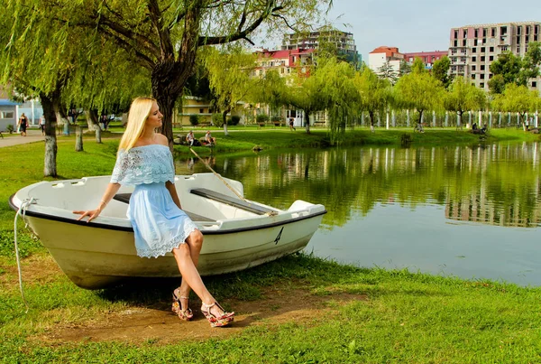 Flicka i en blå klänning placering på den gamla båten vid sjön. — Stockfoto