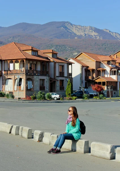 Menina viajante sentado, na cidade Mtskheta, Geórgia. Montanhas ensolaradas e construção ao fundo . — Fotografia de Stock