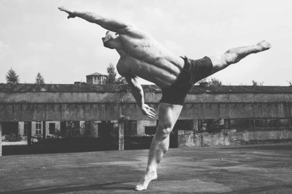 Çağdaş sanat dansı. Endüstriyel binada çıplak gövdeli genç dansçı. Siyah ve beyaz. Sokak şehir yaşam tarzı.